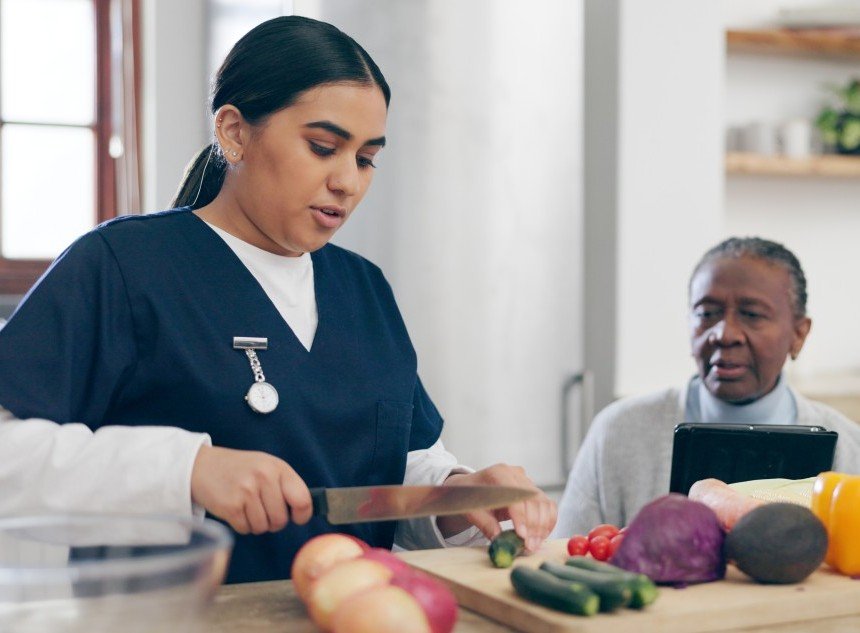 Caregiver helping a senior woman prepare a healthy meal with fresh vegetables
